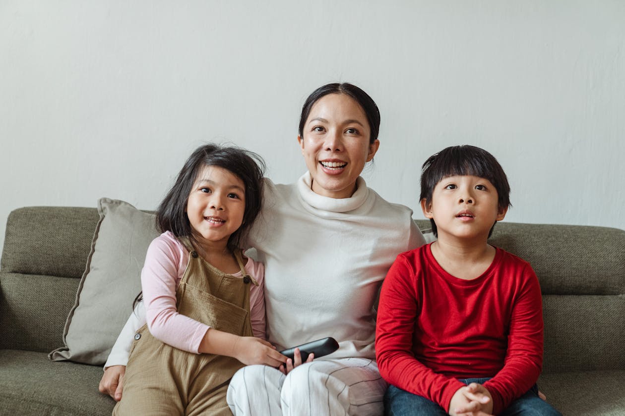 Family watching IPTV on a wall-mounted TV with remote in hand